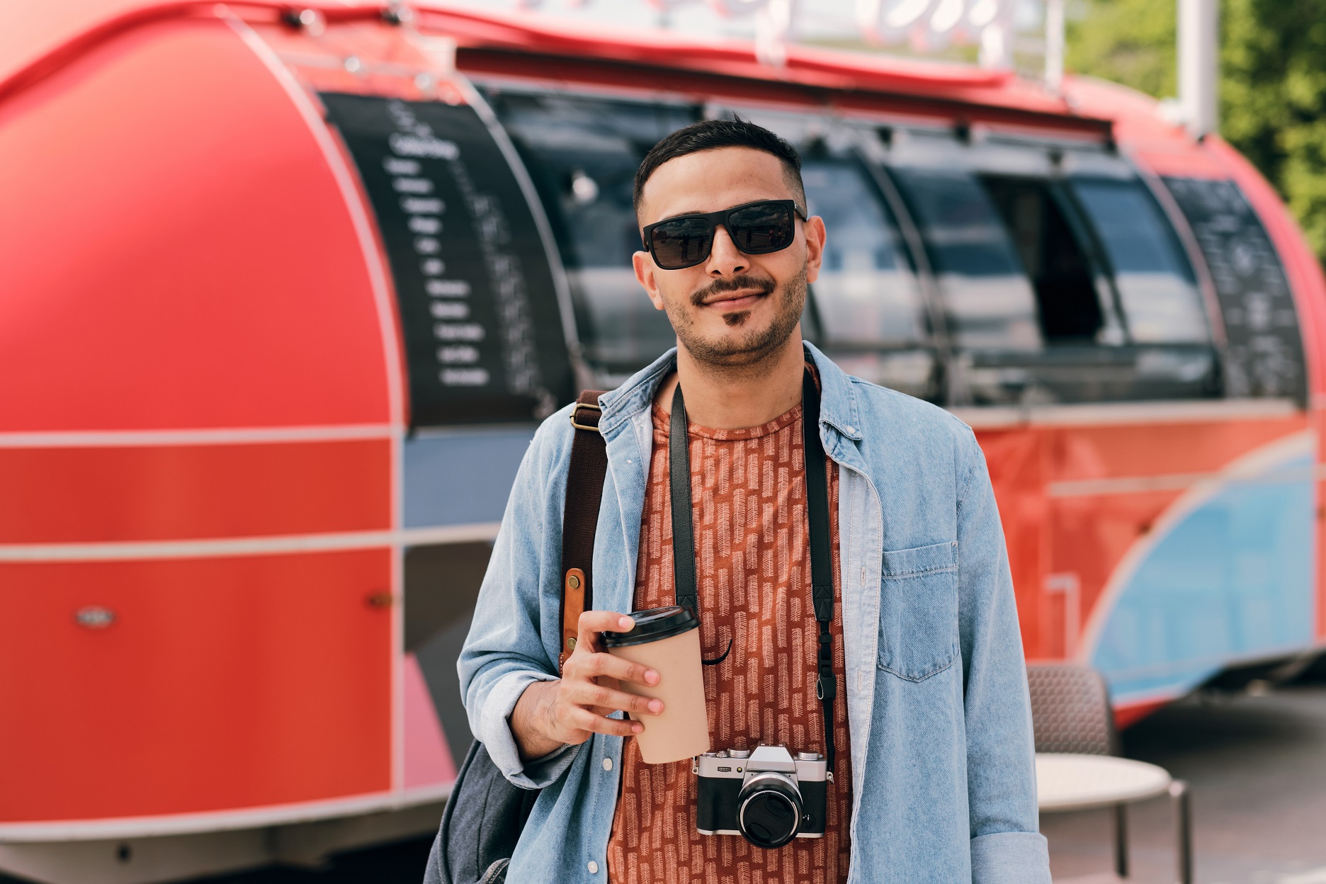 Young male photographer with drink and photocamera